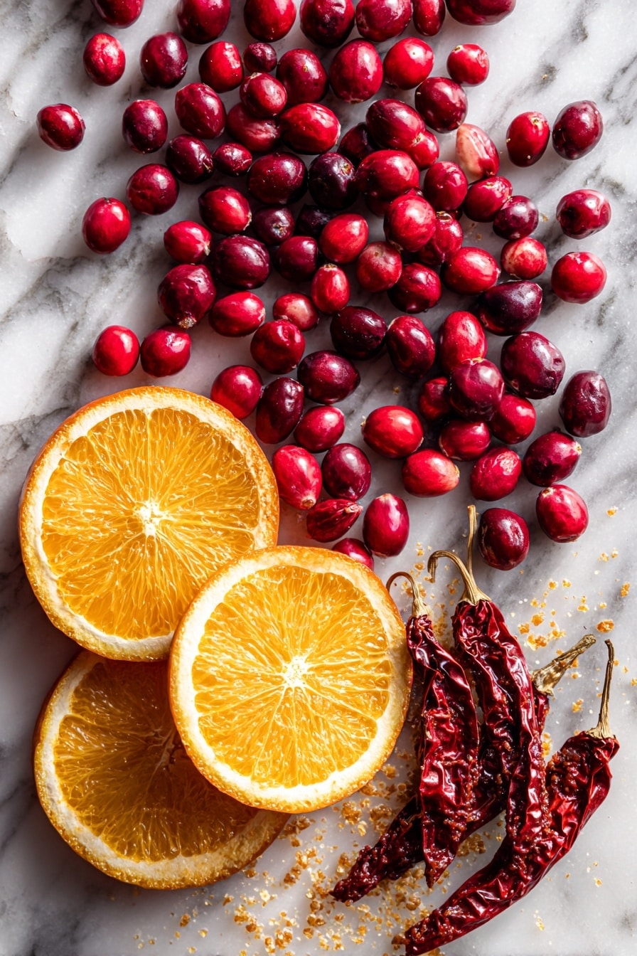 Flat lay of fresh bright red cranberries clustered with a few loose berries scattered around, a vibrant orange slice with juicy texture, deep red chipotle peppers with wrinkled skin, a small bowl of rich, smoky red adobo sauce, and a few diced chipotle pieces showing their spicy seeds, all arranged naturally with contrasting colors and textures placed on white marbled surface, photo taken with an iphone --ar 2:3 --v 7 - Chipotle Cranberry Chutney, spicy cranberry sauce, holiday chutney recipe, easy fruit chutney, smoky cranberry relish