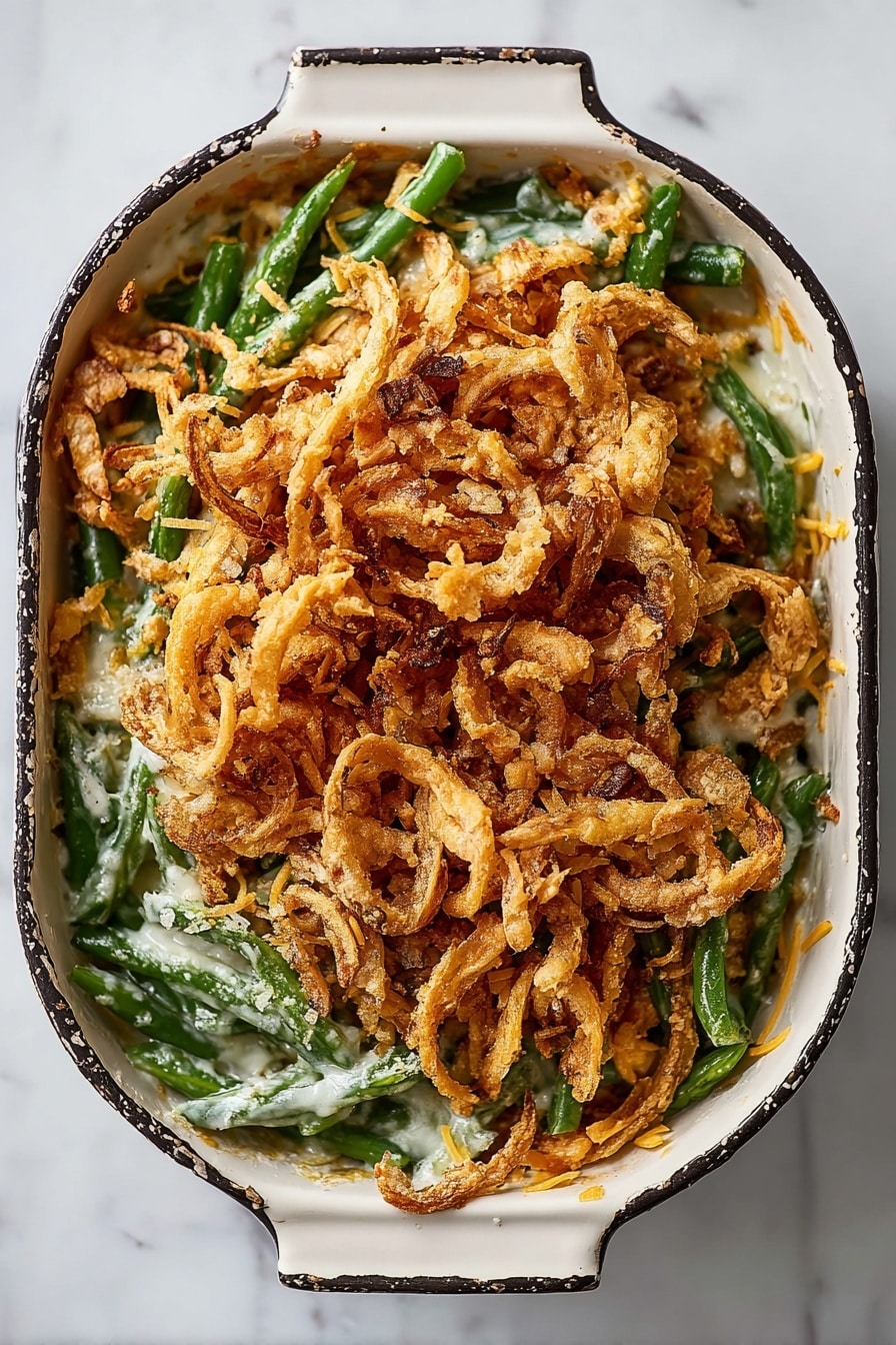 A black rectangular baking dish is filled with three main layers. The bottom layer shows fresh green beans mixed with a creamy white sauce. The middle layer is sprinkled with white grated cheese, adding a slight powdery texture over the green beans. The top layer is a large pile of crispy fried onion strings, golden brown in color with a crunchy texture, covering most of the dish. The dish is on a white marbled surface with some scattered crumbs around it. Photo taken with an iphone --ar 2:3 --v 7 - Green Bean Casserole with French Fried Onions, homemade green bean casserole, holiday green bean casserole, crispy French fried onions recipe, classic Southern green bean dish