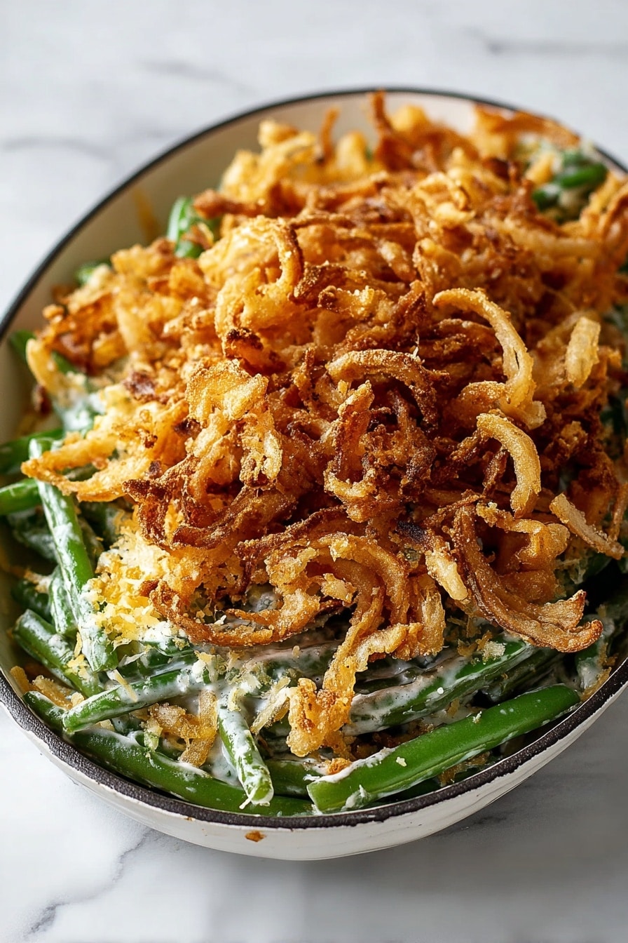 A rectangular black baking dish holds three visible layers of food. The bottom layer consists of green beans with a bright green color, mixed with small mushrooms, spread evenly. The middle layer is a light cream sauce sprinkled with grated cheese that covers the green beans. The top layer is a large pile of crispy, golden-brown fried onion strings, filling the dish's surface. The dish sits on a white marbled surface, with a beige cloth in the top left corner and some green leaves in the top right. Scattered crumbs and onion pieces are around the dish. Photo taken with an iphone --ar 2:3 --v 7 - Green Bean Casserole with French Fried Onions, homemade green bean casserole, holiday green bean casserole, crispy French fried onions recipe, classic Southern green bean dish